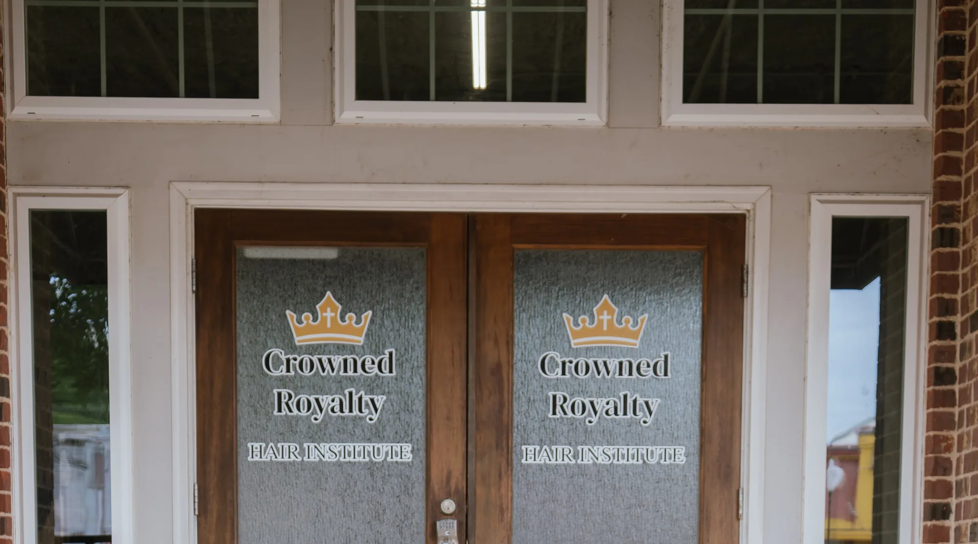 The branded entrance doors of Crowned Royalty Hair Institute